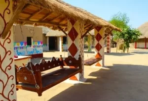 A traditional, colorful Bhunga mud hut featuring a wooden swing chair in Hodka village, highlighted on the 12 Days Trip to Gujarat.