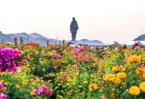 The breathtaking Statue of Unity towering over the vibrant Valley of Flowers, featured on the 7 Days Gujarat Honeymoon Tour Package.