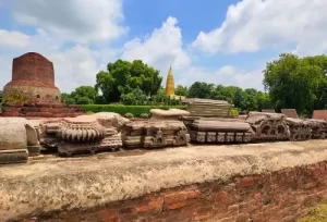 The massive 34-meter-tall cylindrical brick architecture of the Dhamek Stupa surrounded by ancient monastery ruins, explored during a Sarnath Buddhist heritage trip from Varanasi.
