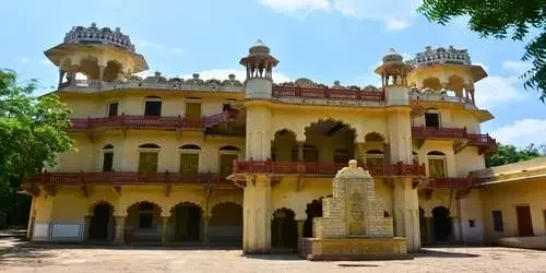 The imposing architecture of the historic Garh Palace in Jhalawar, showcasing traditional Rajput balconies and intricate stone brackets under a clear sky.