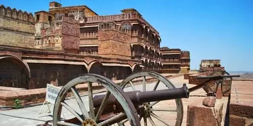 An ancient iron cannon resting on the roof of the majestic Mehrangarh Fort, overlooking the blue-painted houses of Jodhpur, Rajasthan.