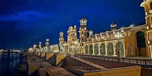 The spectacular Chambal Riverfront in Kota beautifully illuminated at night, featuring traditional Rajasthani ghats, intricate sculptures, and vibrant light reflections on the water.