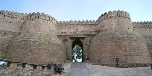 A breathtaking view of the massive, winding 36-kilometer fortified wall of Kumbhalgarh Fort stretching across the lush green Aravalli hills in Rajasthan.